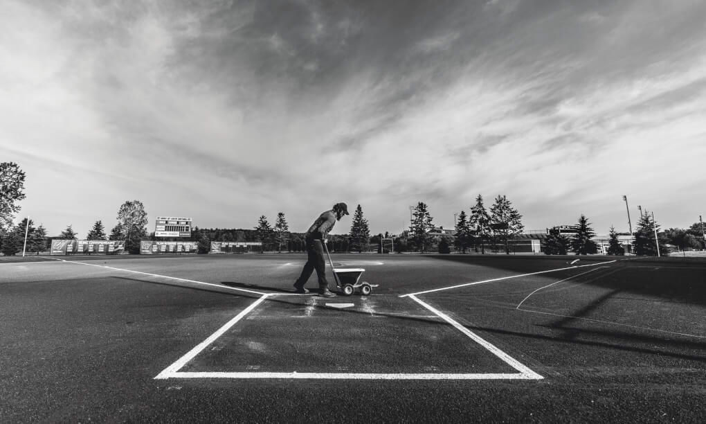 Ashley Fleser paints fresh lines of chaulk on the softball field